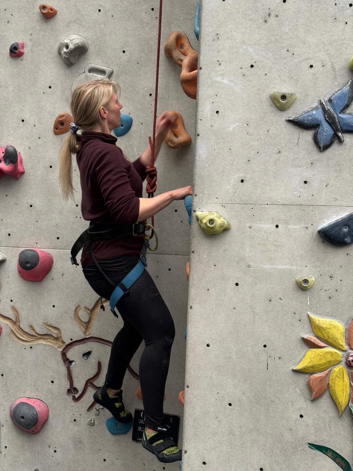 Danielle clipped into a rope on an indoor climbing wall